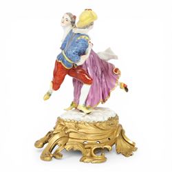 Mid 18th century Meissen figure group, The Tyrolean Dancers, circa 1740, modelled as two swirling figures with their arms linked, he in yellow hat with red rosette, blue jacket, red breeches with red rosette, and yellow shoes with green rosette, she in white blouse with red ribbons, yellow and red bodice, white apron over puce skirt and yellow shoes with green rosettes, her hair fashioned into two plaits secured by red ribbon, upon a shaped mound base, within a scrolling gilt metal mount, with blue crossed swords mark to base, overall H19cm
