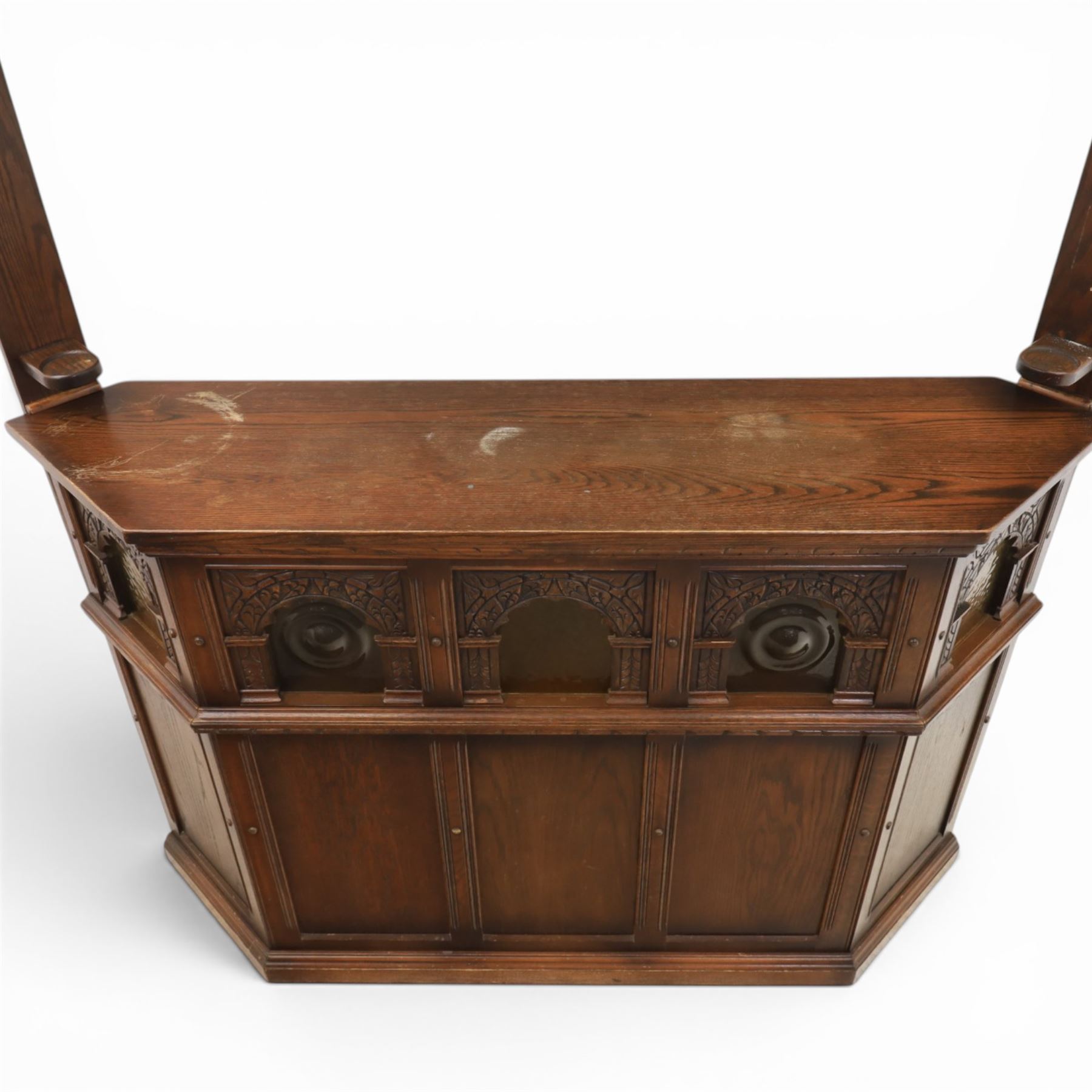 Old Charm - carved oak bar with three bar stools and associated Old Charm drinks cabinet, carved top with channels for glassware beneath, bar surface above glazed panels, shelves for glassware to the back, associated Old Charm drinks cabinet with fall front linenfold carving, above twin doors with shelved interior