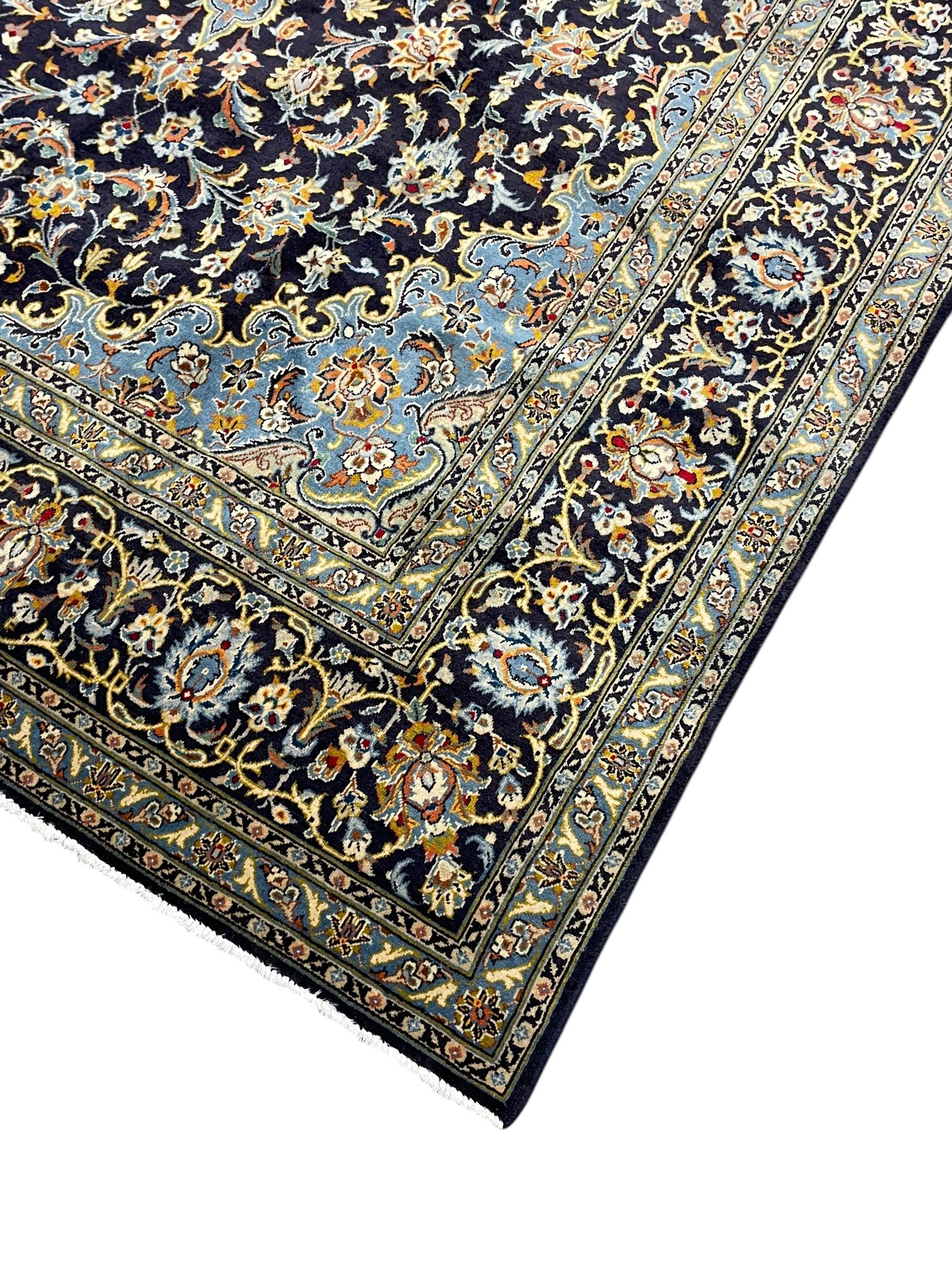 Persian Kashan indigo ground carpet, floral pattern light blue ground central medallion and spandrels, the fielding decorated with interlacing leafy branches and palmettes, the repeating floral pattern border enclosed within guard stripes