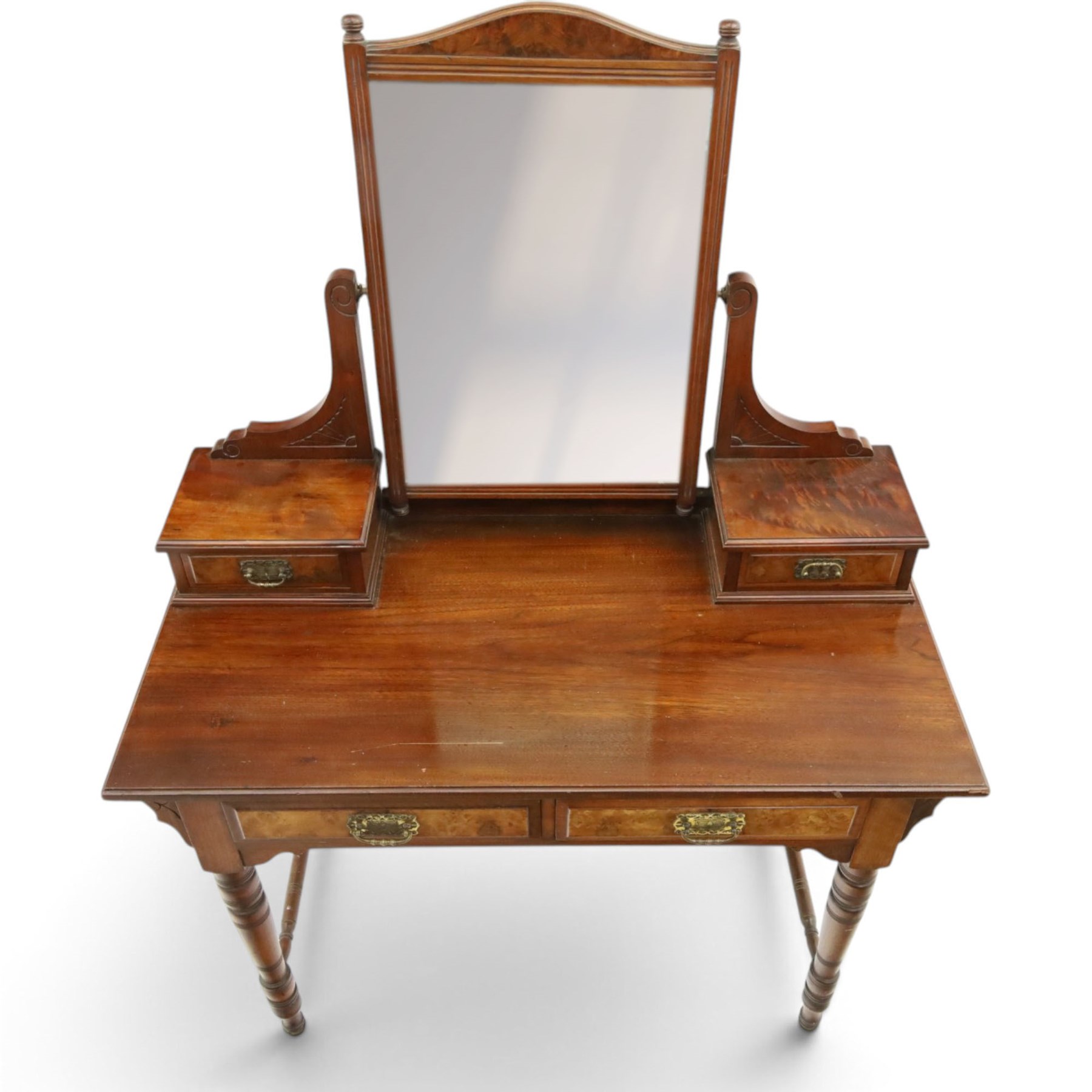 Late Victorian figured walnut and mahogany dressing table, raised swing-mirror back over trinket drawers, fitted with two drawers with brass Aesthetic Movement handles, on ring-turned supports with ceramic castors