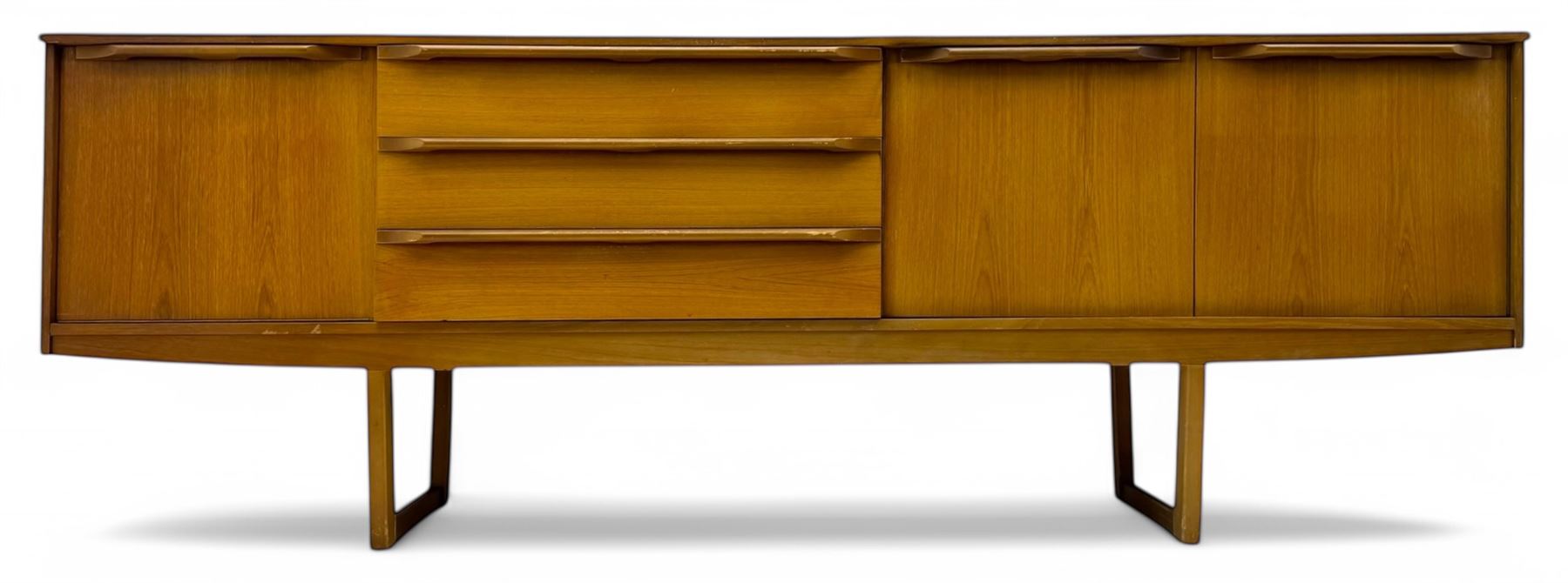 Mid-20th century teak sideboard, fitted with a fall-front cupboard, three drawers including a green baize-lined cutlery drawer, and a double cupboard, with integrated handles, on sleigh supports
