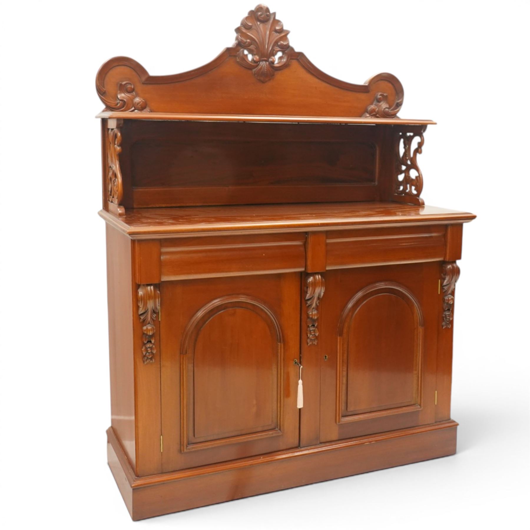 Victorian mahogany chiffonier, the superstructure with shaped back and pierced side supports above a shelf, moulded top over twin arched panel doors enclosing cupboard interior, with carved scroll brackets, on plinth base