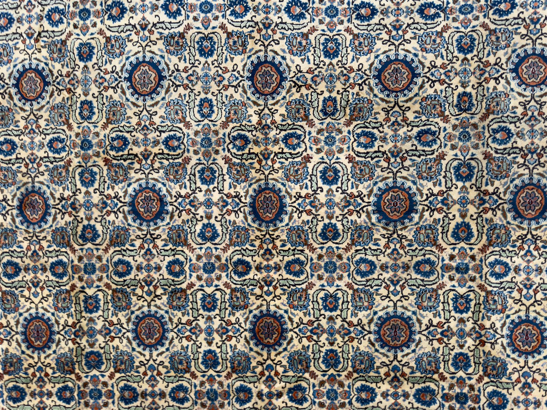 Northwestern Persian Tabriz hand-knotted carpet, the ivory ground with an all-over repeating Herati pattern of stylised palmettes, rosettes and serrated leaves in shades of indigo, terracotta and sky blue, framed by a dark blue border of arabesque vines and scrolling foliage between floral guard stripes, from the region of Tabriz