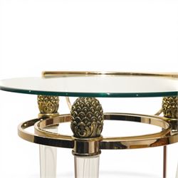 Hollywood Regency style gilt metal and glass serving trolley, circular top in a polished brass surround with three pineapple finials, supported on clear column legs, lower glass shelf enclosed by a brass gallery, terminating in castors