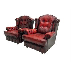 Mid-20th century three seat wing back sofa, upholstered in oxblood buttoned leather with studwork, on shepherd castors; pair matching mid-20th century chesterfield style armchairs (90cm x 88cm x 98cm)