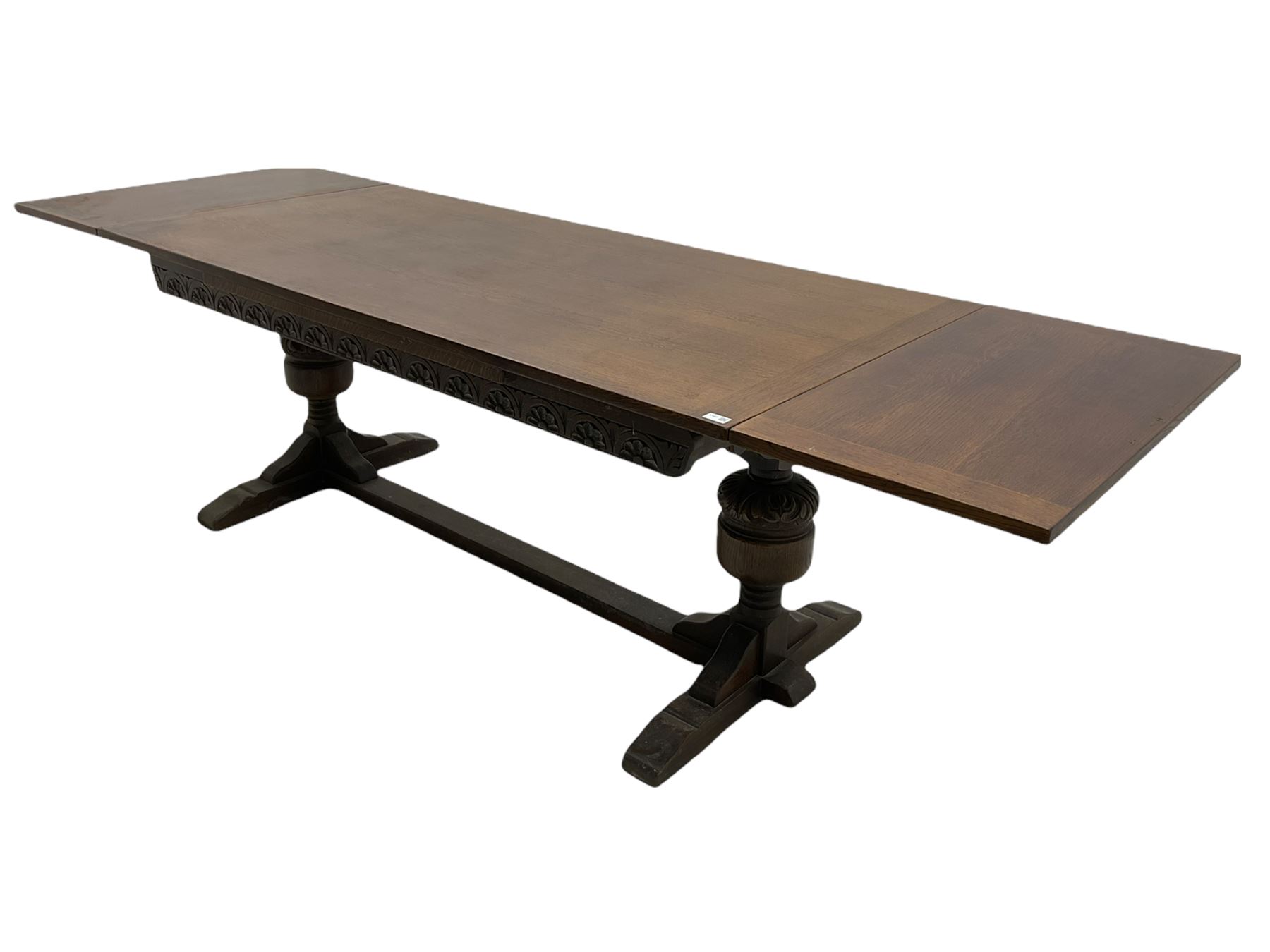 20th century oak drawer leaf extending dining table, two foliage carved baluster supports on sledge feet joined by floor stretcher 