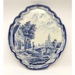 A 20th century Delft style blue and white faience pottery plaque, of shaped form decorated with a riverside scene, H36cm L32cm.