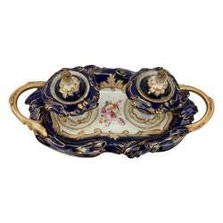 19th century porcelain inkstand, the oblong twin handled base centrally painted with a floral bouquet, flanked by two footed inkwells and covers, with rococo-inspired acanthus moulded borders and handles, pattern no. 2/3339, L26.5cm 