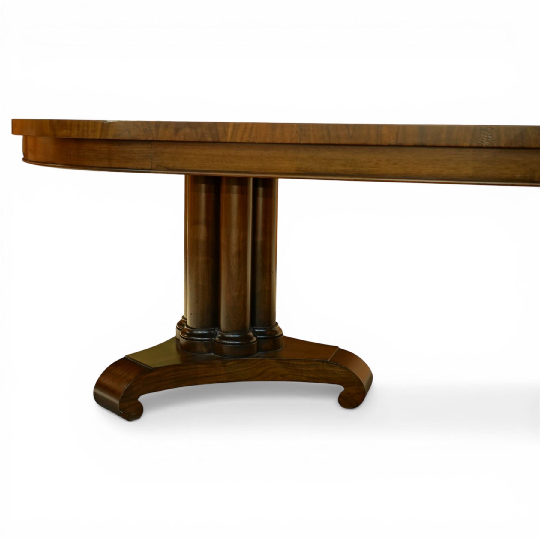 Late 20th century Regency design walnut twin pedestal dining table, the oval top with radial sunburst veneered ends centred by roundels, upon twin pedestal turned column supports, issuing to down swept triform bases