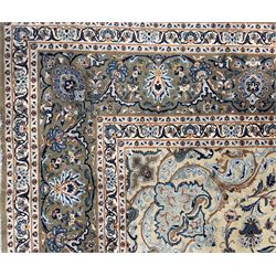 Central Persian Kashan hand-knotted carpet, ivory field with scrolling vines, palmettes, and rosettes around a cusped medallion with pendants and spandrels within a blue ground border of palmettes and flowerheads, 388cm x 300cm