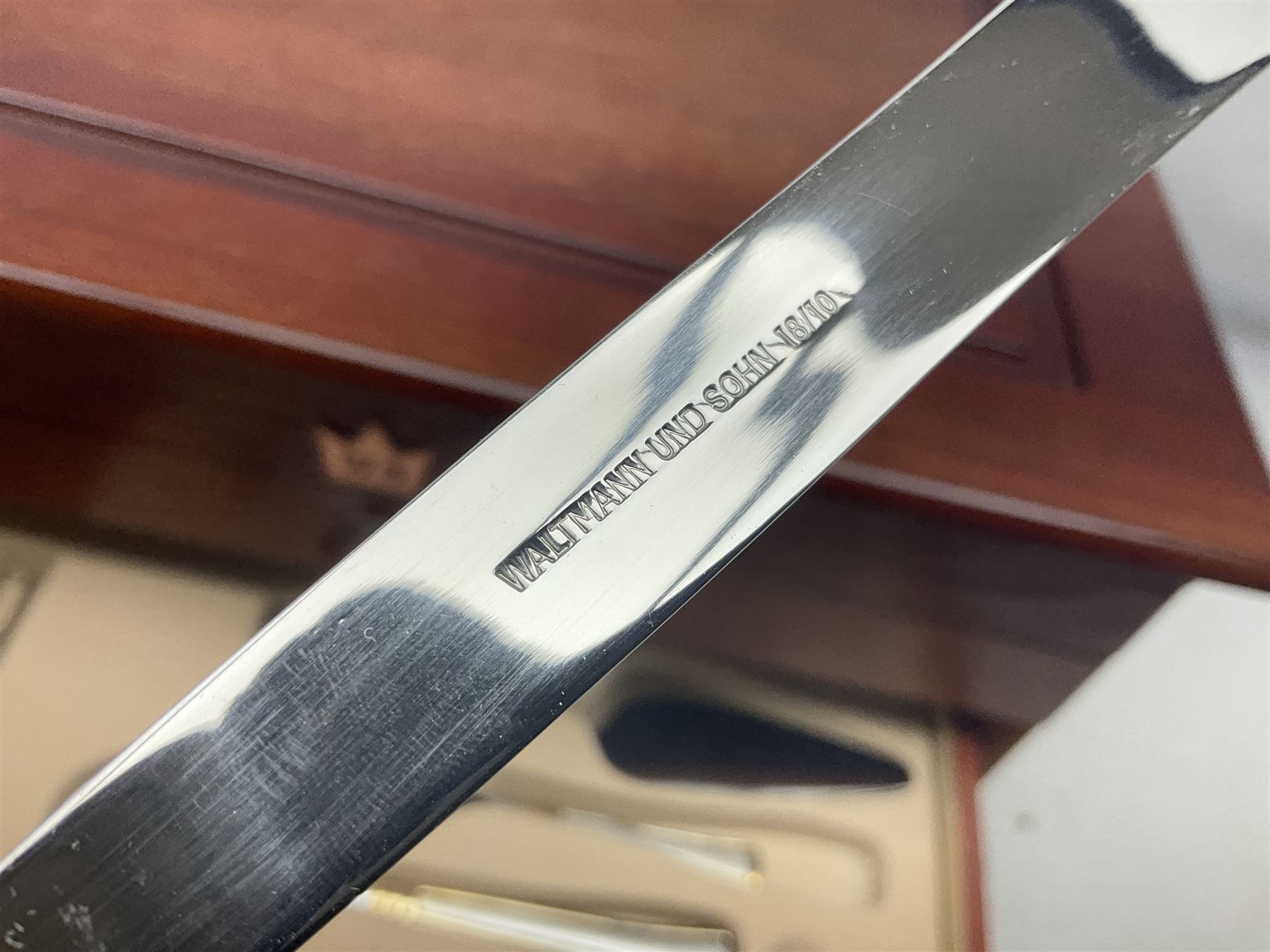 Waltmann und Sohn part canteen of stainless steel and gilt cutlery, the stained wood case with hinged lid above two fitted drawers, L48cm