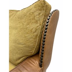 Pair of 1930’s carved oak framed club chairs, upholstered in tan studded leather with beige fabric loose cushions