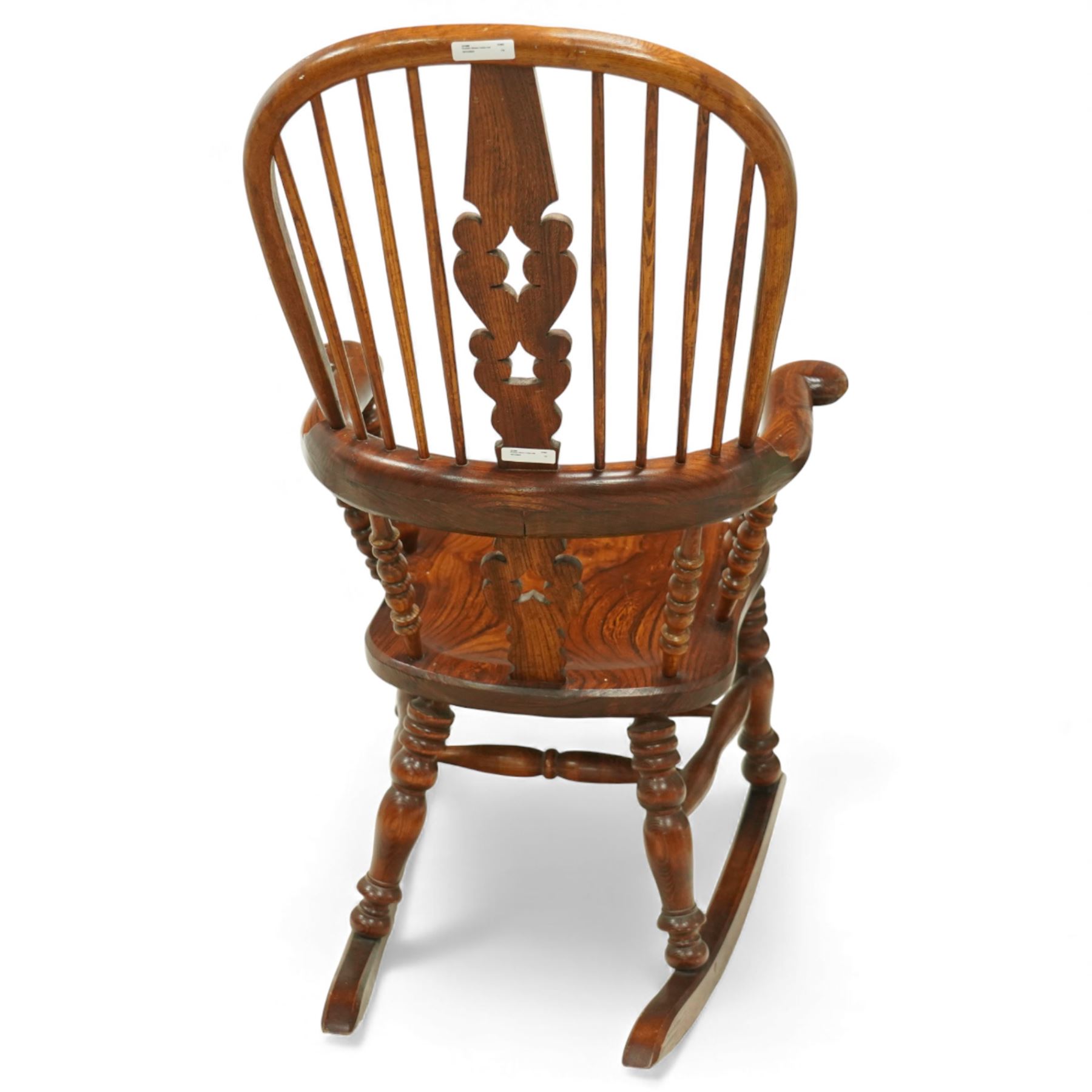 Broadarm Windsor rocking chair, arched crest rail enclosing turned spindle back with pierced splat, wide shaped arms with turned supports, solid elm seat, raised on turned legs united by double stretchers, on swept rockers
