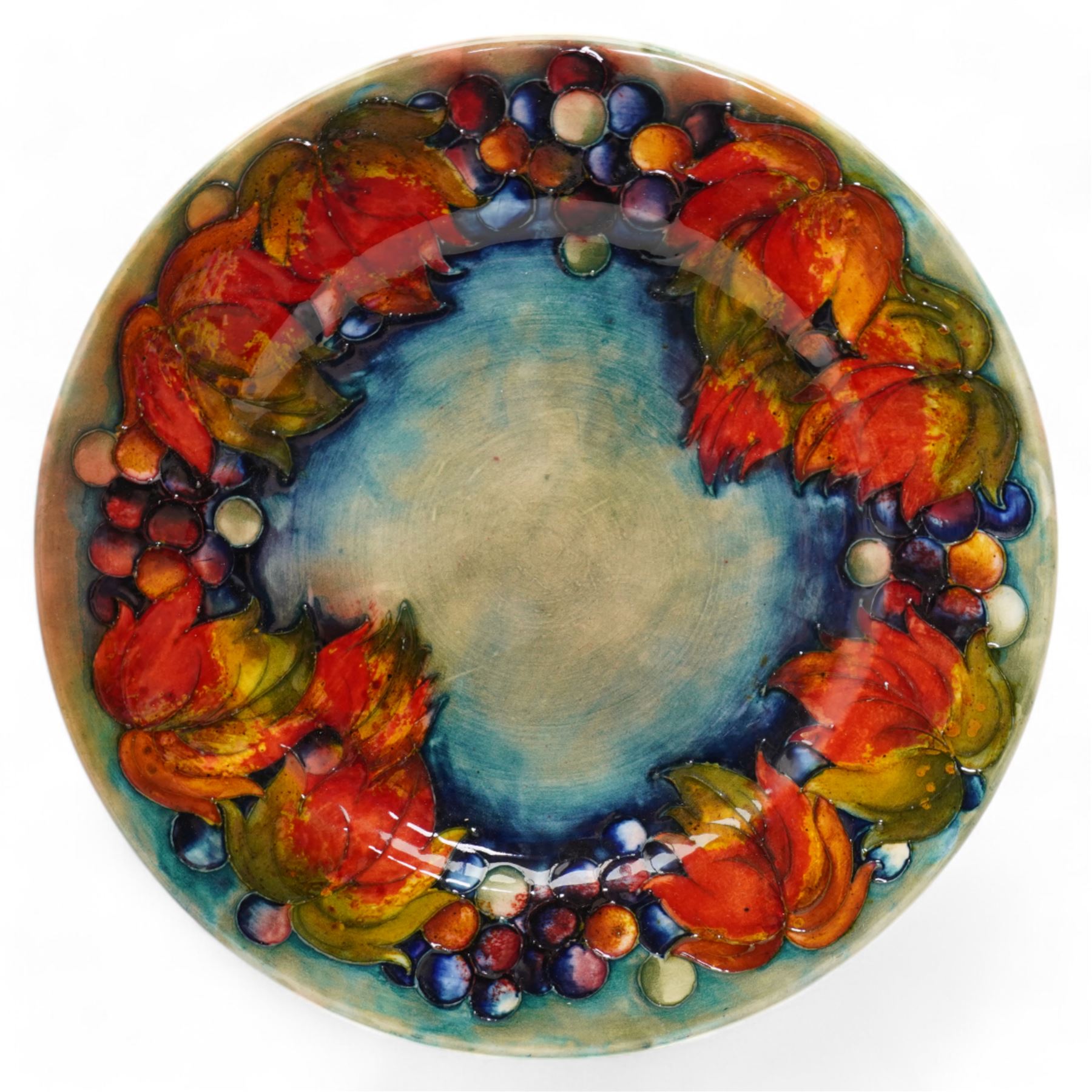 William Moorcroft plate decorated with the leaves and berries pattern, with signature mark and 'Potter to H.M. the Queen' to base, with stand, D29cm