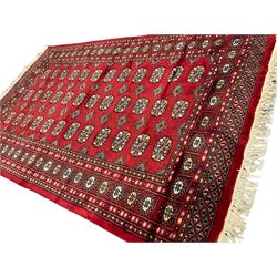 Persian Bokhara crimson ground rug, the field decorated with repeating Gul motifs and lozenges, the multi-band border with stylised plant motifs with black outlines