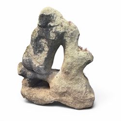 Carved composite stone garden figure, depicting a seated child with folded arms, weathered finish with moss and lichen growth, raised on an integral naturalistic base