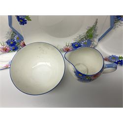 Shelley Strand shaped tea wares, decorated with blue and pink daisies upon a white ground, comprising four teacups, four saucers, three tea plates, milk jug, sugar bowl and cake plate, all with printed green mark beneath and painted pattern no 12216
