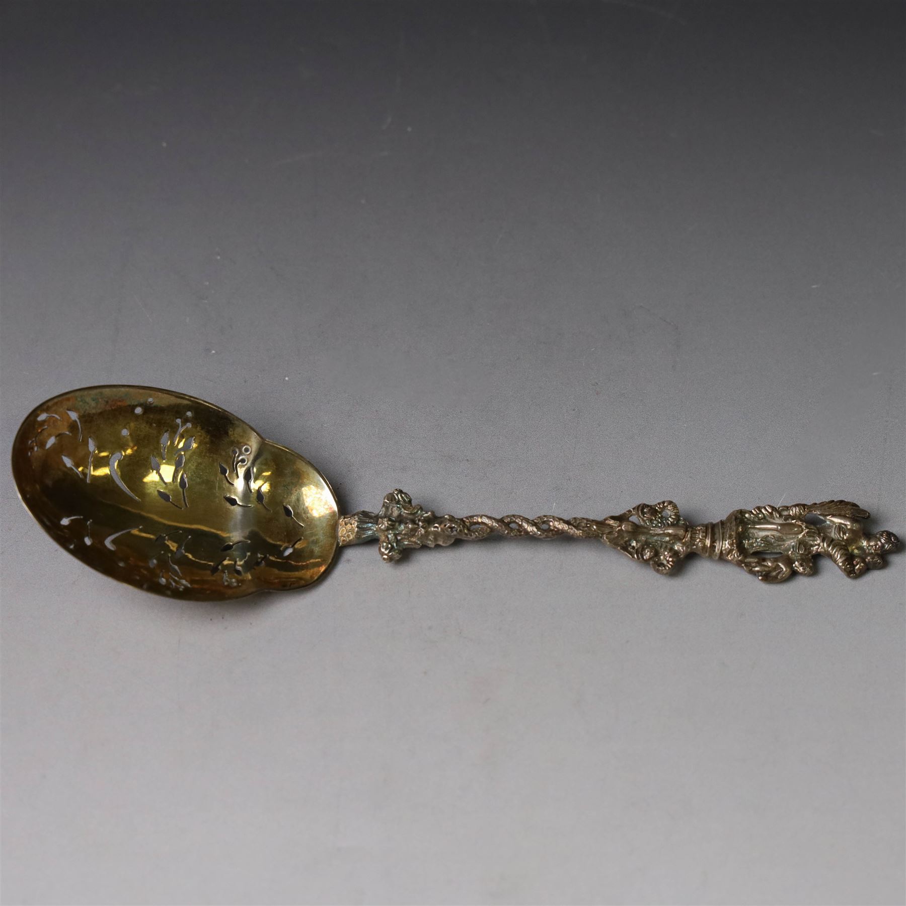 Late Victorian apostle topped sifting spoon, the finial depicting St Christopher, with entwined serpent handle and pierced gilt bowl, hallmarked Mappin & Webb, London 1890, in fitted retailers box for Catchpole and Williams Ltd