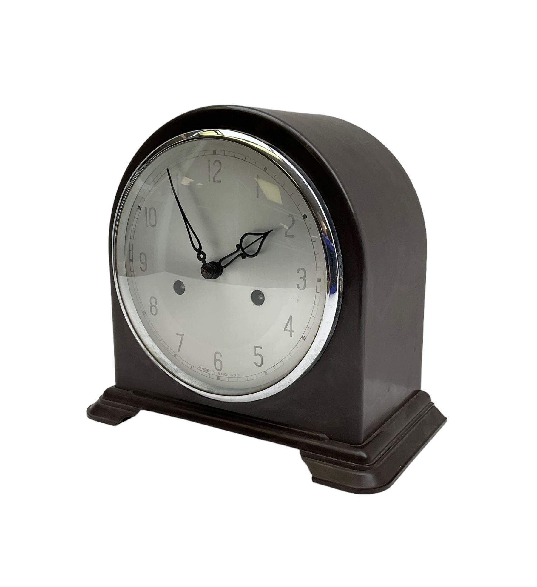 Enfield- English 1950's 8-day mantle clock in a round topped brown Bakelite case on splayed feet, with a glazed chrome bezel and silvered dial with Arabic numerals and original pierced hands, twin train spring driven movement, sounding the hours and half-hours on a coiled gong. With pendulum & key.  