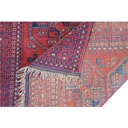 Afghan red ground Bokhara rug, the field decorated with two rows of large Gul motifs, within geometric pattern borders 