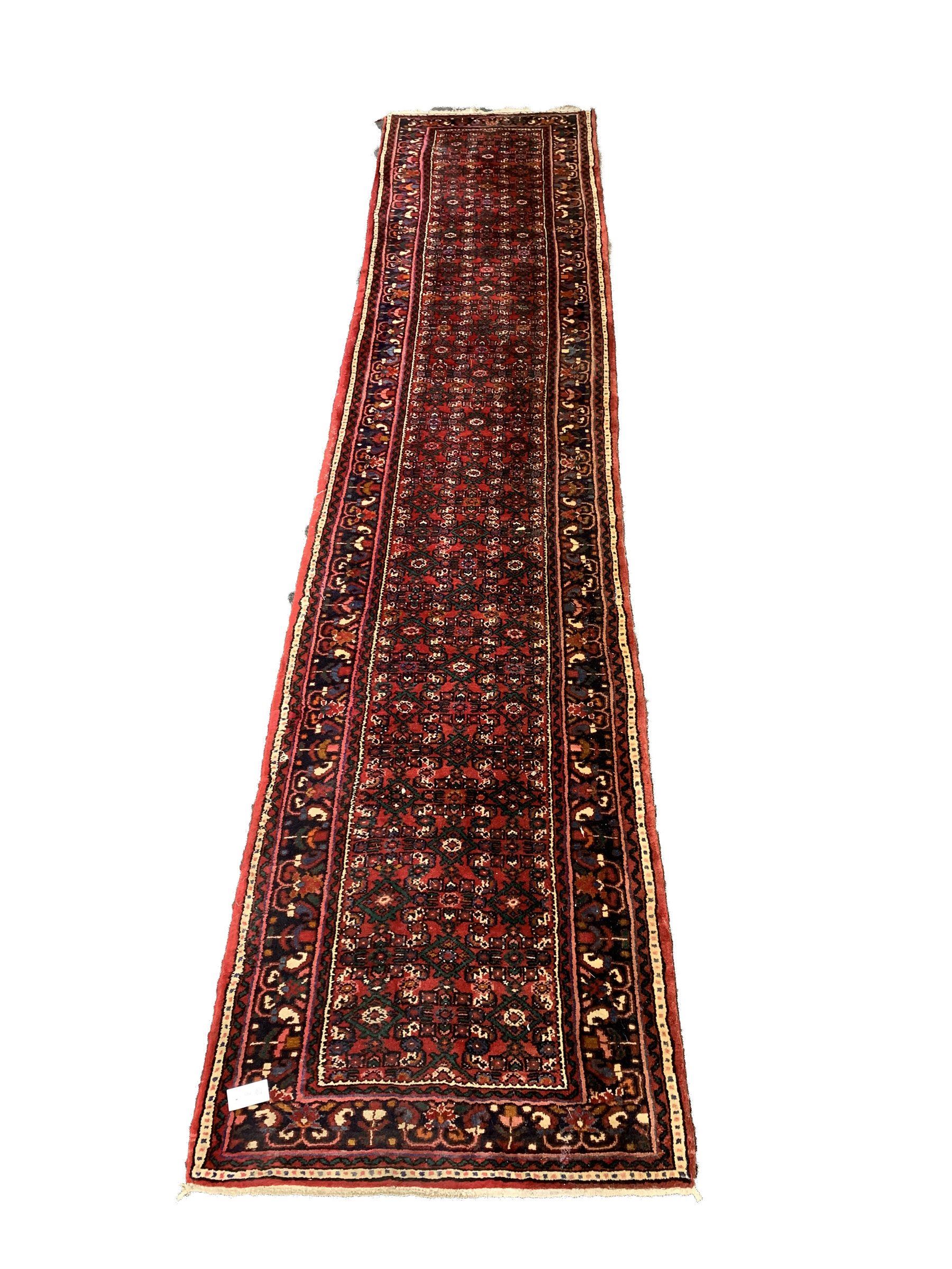Central Asian runner rug, with repeating lozenge motif on busy red field, stylised foliate to border, 86cm x 400cm