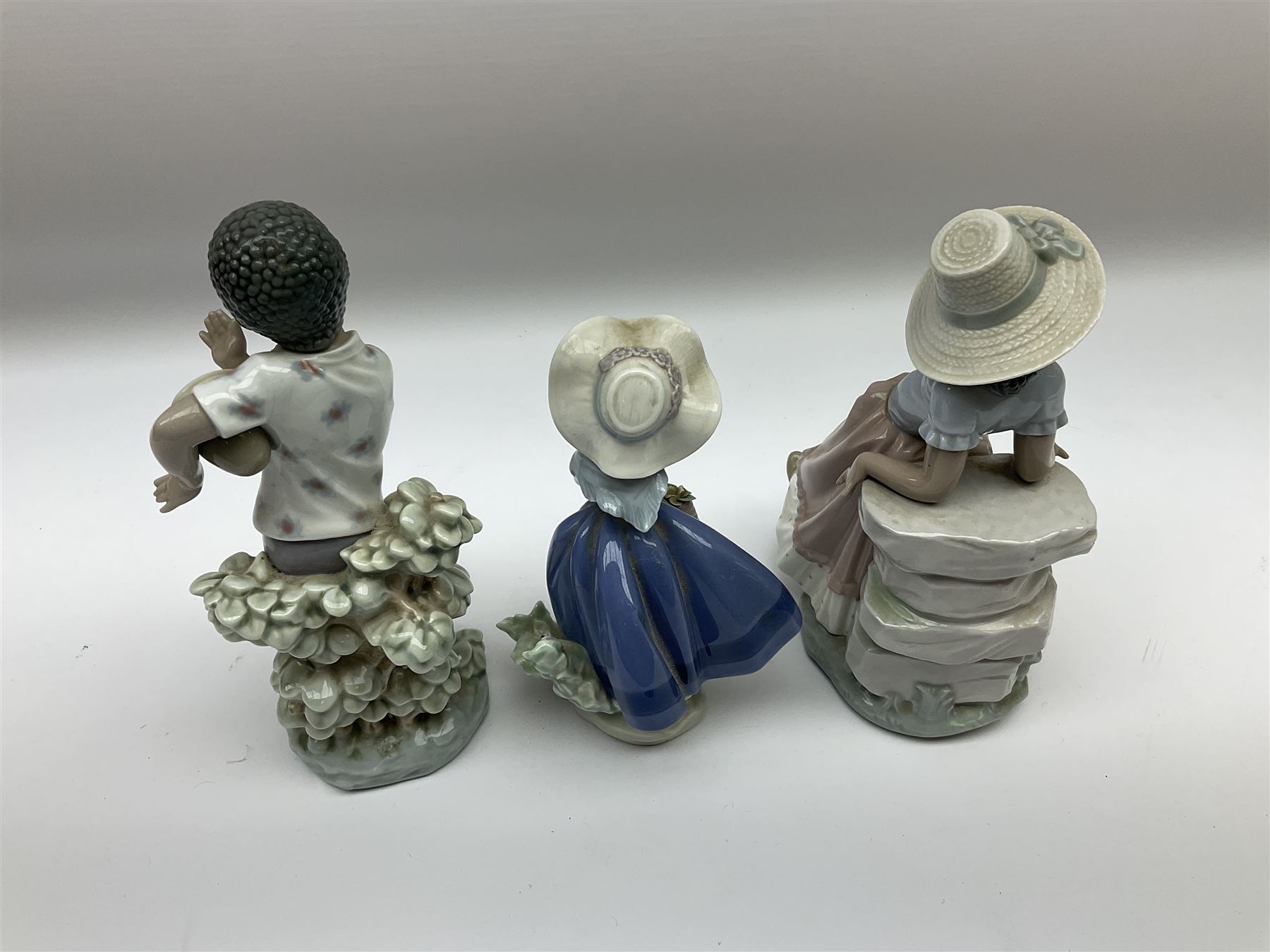 Pair of Lladro figures designed by Jose Roig, Bongo Beat no. 5157 and A Step in Time no. 5158 and a Lladro figure of a girl with a basket of flowers.
