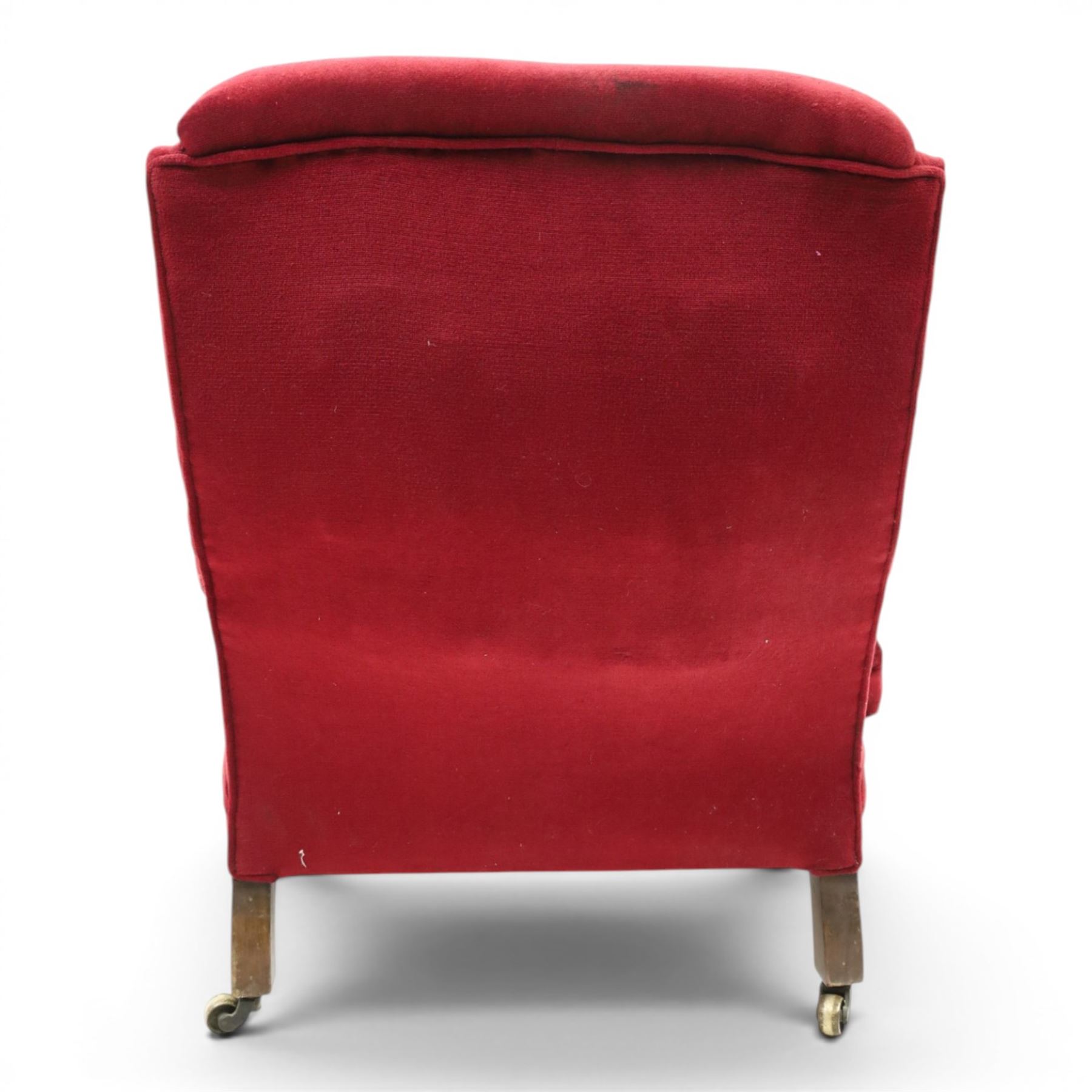 Victorian walnut framed reading open armchair of reclined position, the high sprung back and deep seat upholstered in crimson fabric with matching loose seat cushion, turned arm terminals over turned feet terminating to brass castors