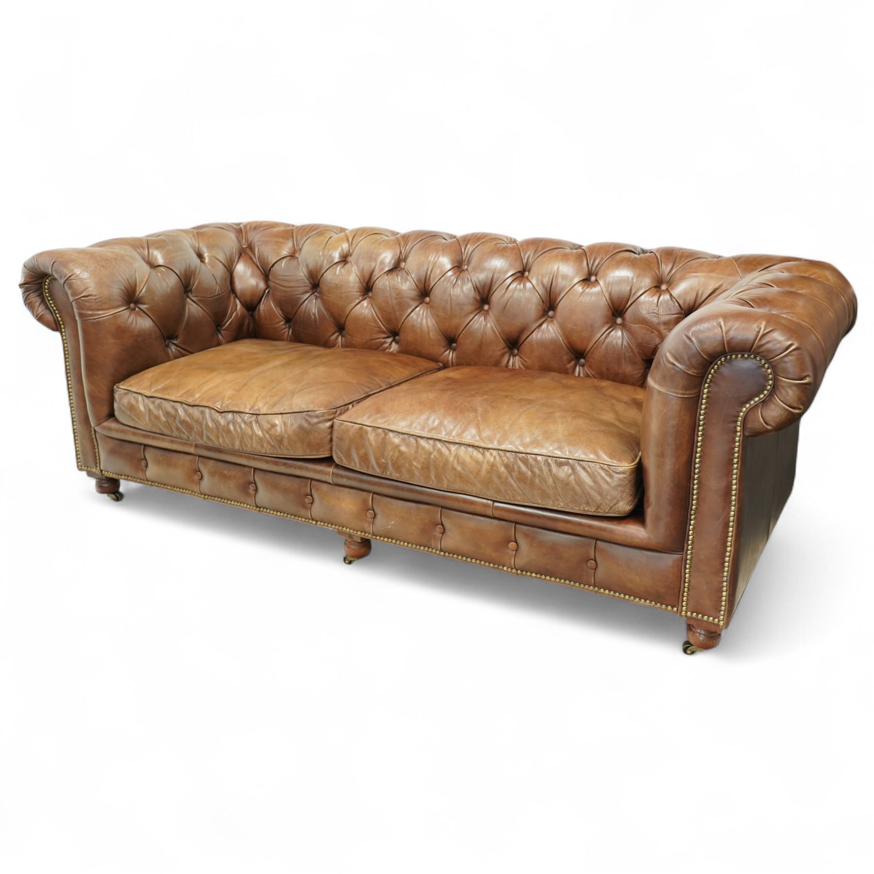 Timothy Oulton, Halo - Late 20th century brown leather Chesterfield settee, the upholstered frame with deep buttoning to back and arms, large scroll terminals with brass studwork, twin seat cushions, raised on castored legs
