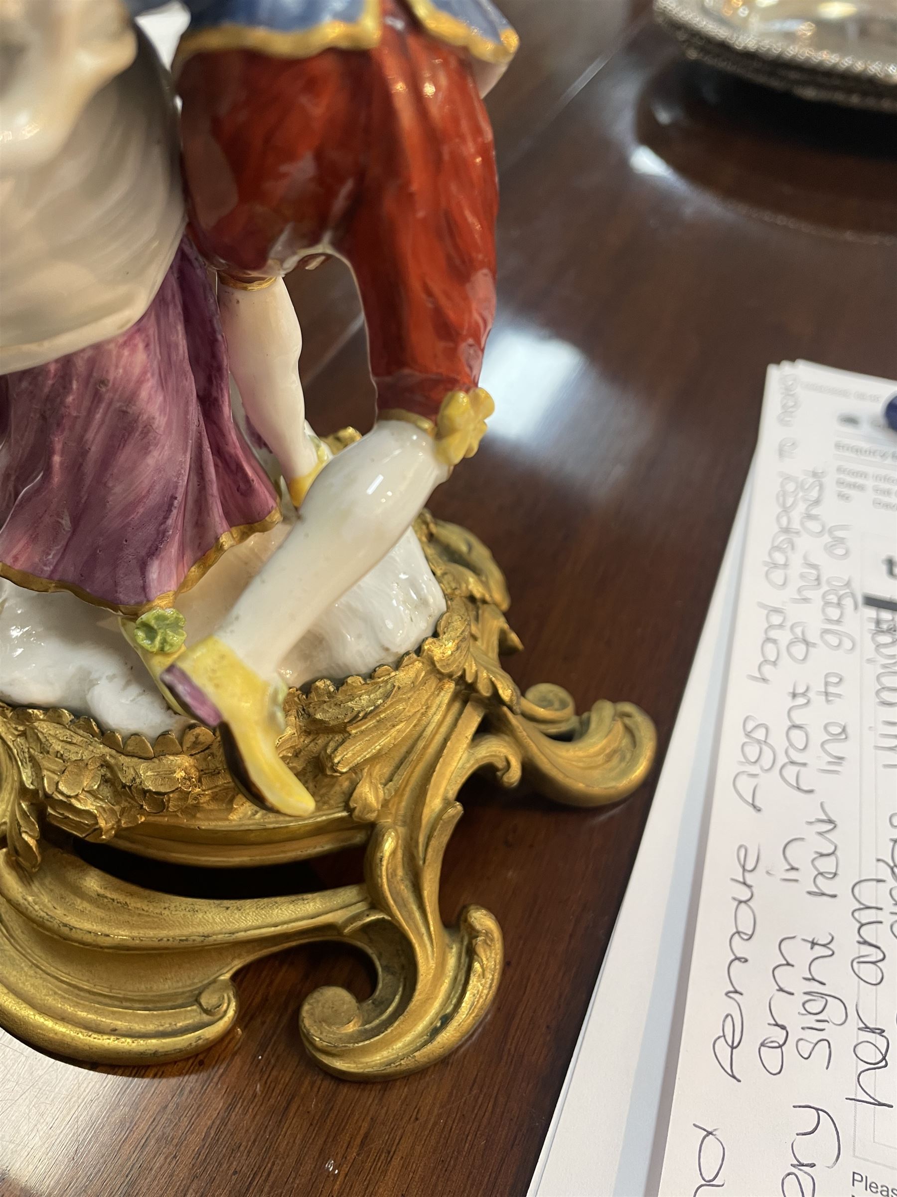 Mid 18th century Meissen figure group, The Tyrolean Dancers, circa 1740, modelled as two swirling figures with their arms linked, he in yellow hat with red rosette, blue jacket, red breeches with red rosette, and yellow shoes with green rosette, she in white blouse with red ribbons, yellow and red bodice, white apron over puce skirt and yellow shoes with green rosettes, her hair fashioned into two plaits secured by red ribbon, upon a shaped mound base, within a scrolling gilt metal mount, with blue crossed swords mark to base, overall H19cm
