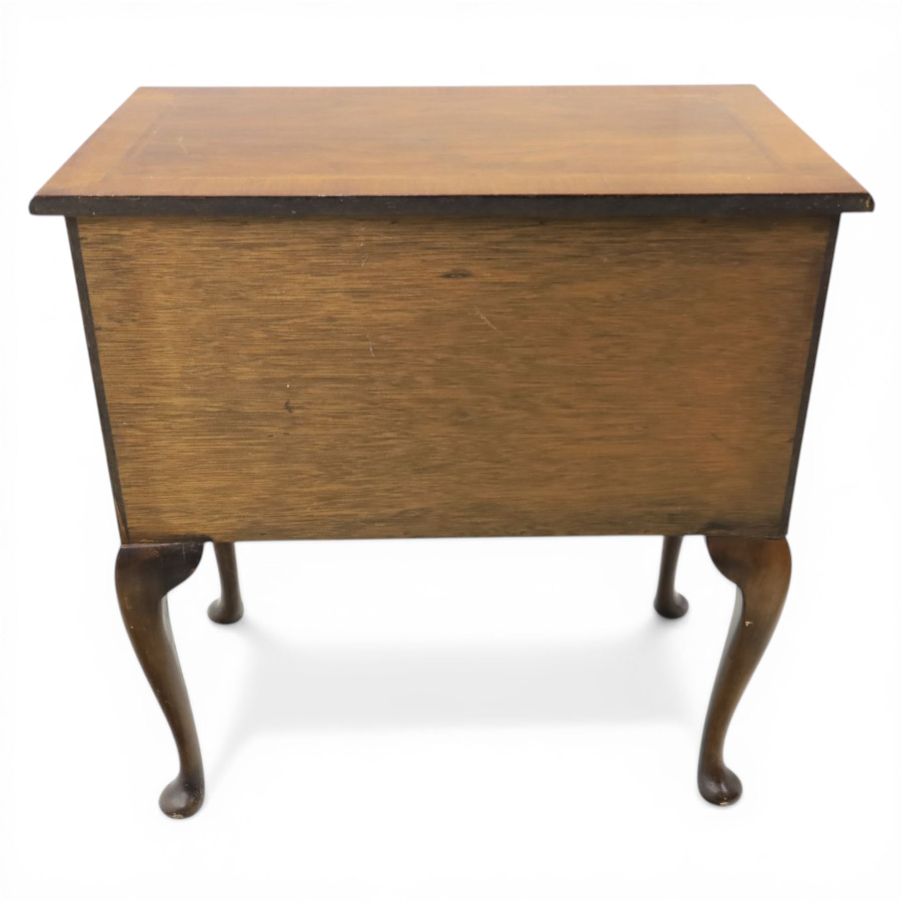 Early 20th century walnut lowboy in Queen Anne style, rectangular crossbanded top over single long drawer and two short drawers with shaped apron, fitted with brass drop handles and backplates, raised on cabriole supports terminating in pad feet