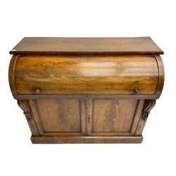 Victorian mahogany roll-top writing desk, top concealing fitted interior with pigeonholes and three drawers, the trisector inset writing surface with writing slope, base fitted with panelled cupboard enclosing single shelf, decorated with scrolled corbels