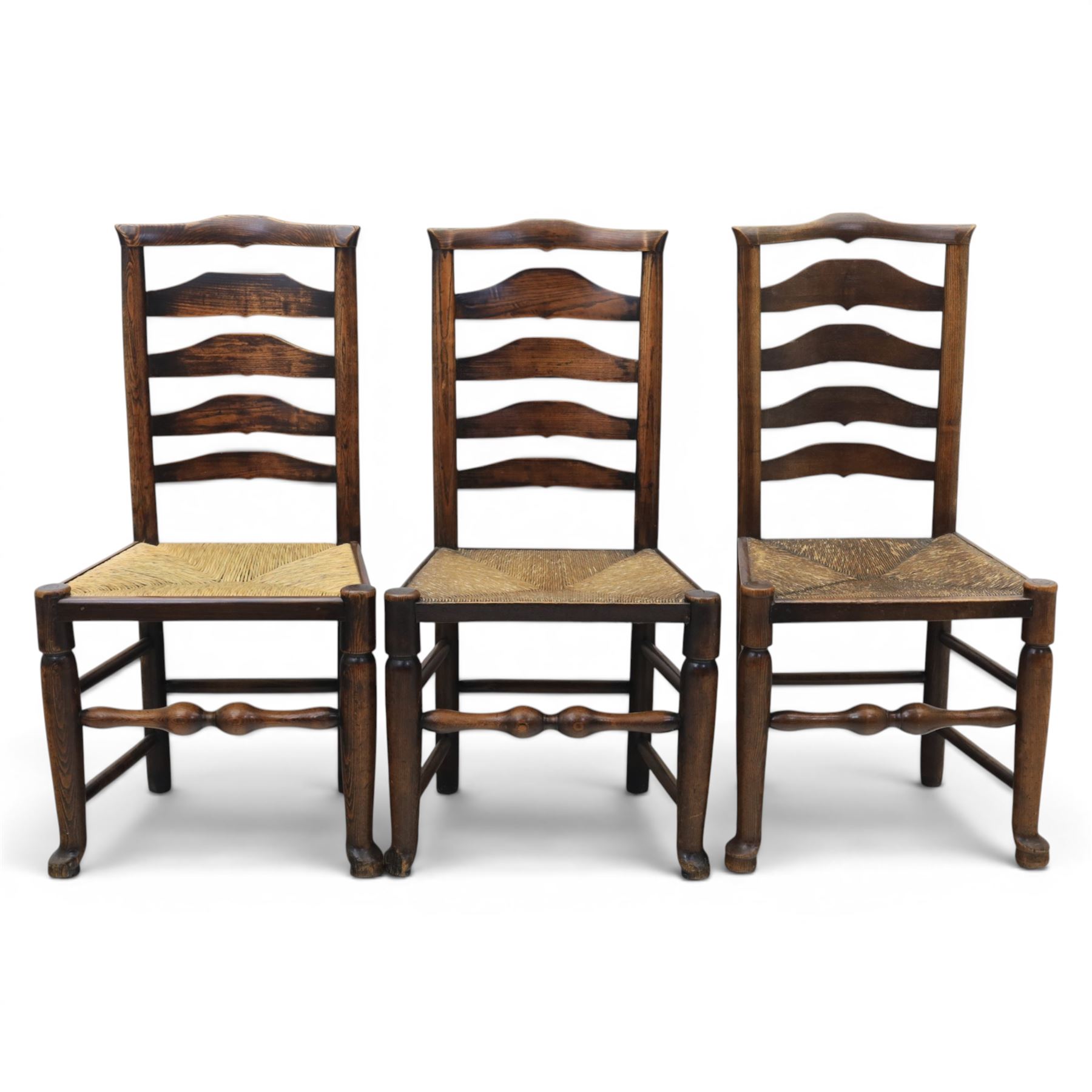 Set of seven (6+1) Georgian design country elm Lancashire dining chairs, ladder backs with rush seats, turned front leg stretcher on pad feet, height of seat 44cm, complete with fitted tie on cushions