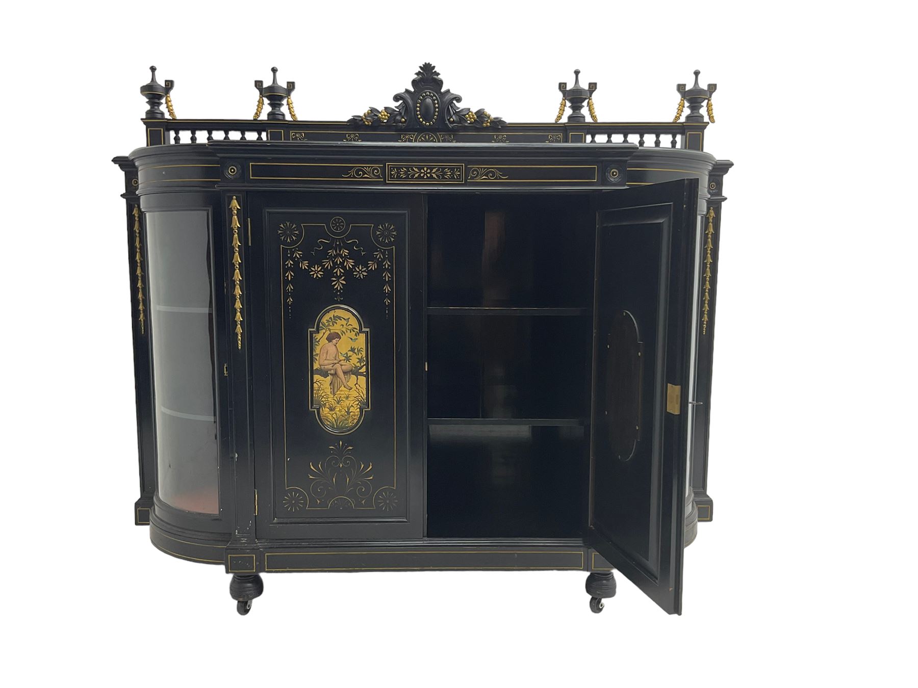 Victorian ebonised credenza side cabinet, raised balustrade back with urn finials and a central carved cartouche, carved and gilded with floral garland decoration, central doors with gilt panels painted with figures sitting over a lake enclosing two shelves, flanked by applied bellflower detail and glazed bow-front side doors, raised on ring turned feet with castors