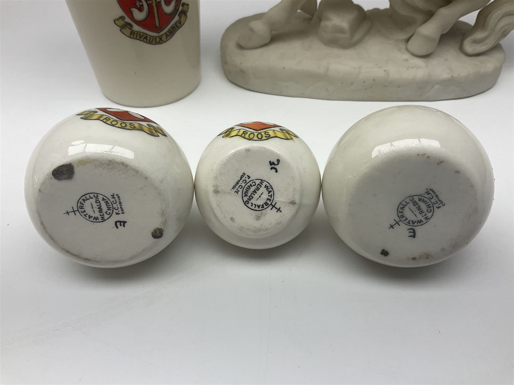 W.H.Goss Parian figure of Lady Godiva, with printed mark beneath, together with a W.H.Goss crested ware Rivaulx Abbey tumbler, and three similar Waterfall Heraldic China crested ware items, Godiva H19cm 