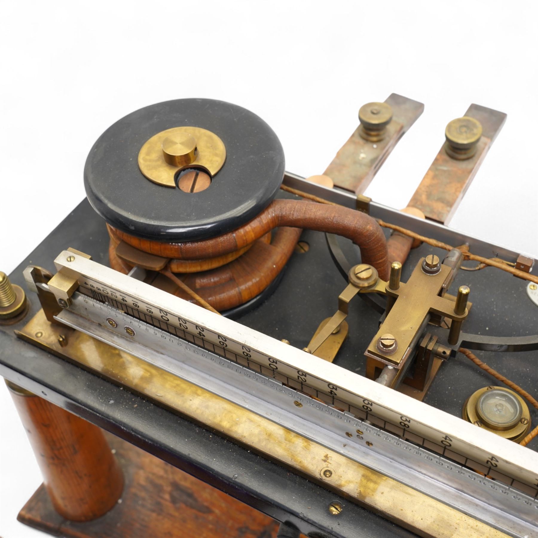 Lord Kelvins Patent electric current balance, no. 823, by Kelvin & James White Ltd Glasgow & London, with two pairs of horizontally mounted coils, suspended beam balance mounted on an ebonite base under glass and brass cover, with box of weights and accessories, raised on three wooden supports, W51cm H37.5cm