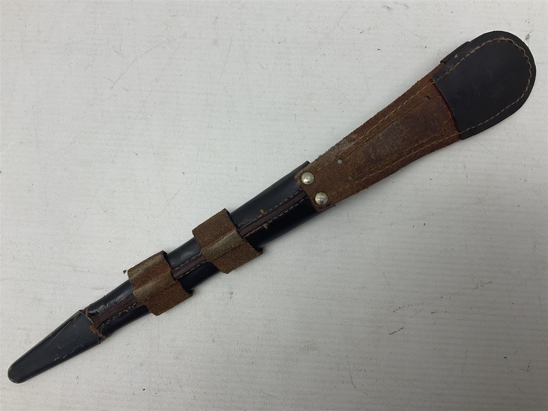 Third Pattern Commando Knife or Dagger with 17.5cm flattened diamond section blade and regulation black painted ribbed copper hilt with brass pommel nut; stamped William Rodgers Sheffield England to the cross-piece; in black painted brass mounted leather scabbard L34.5cm overall