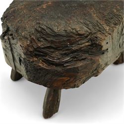 Rustic bog oak stool of oval form with a single solid section with a deeply patinated and textured surface, raised on three tapered stick legs, possibly Irish 