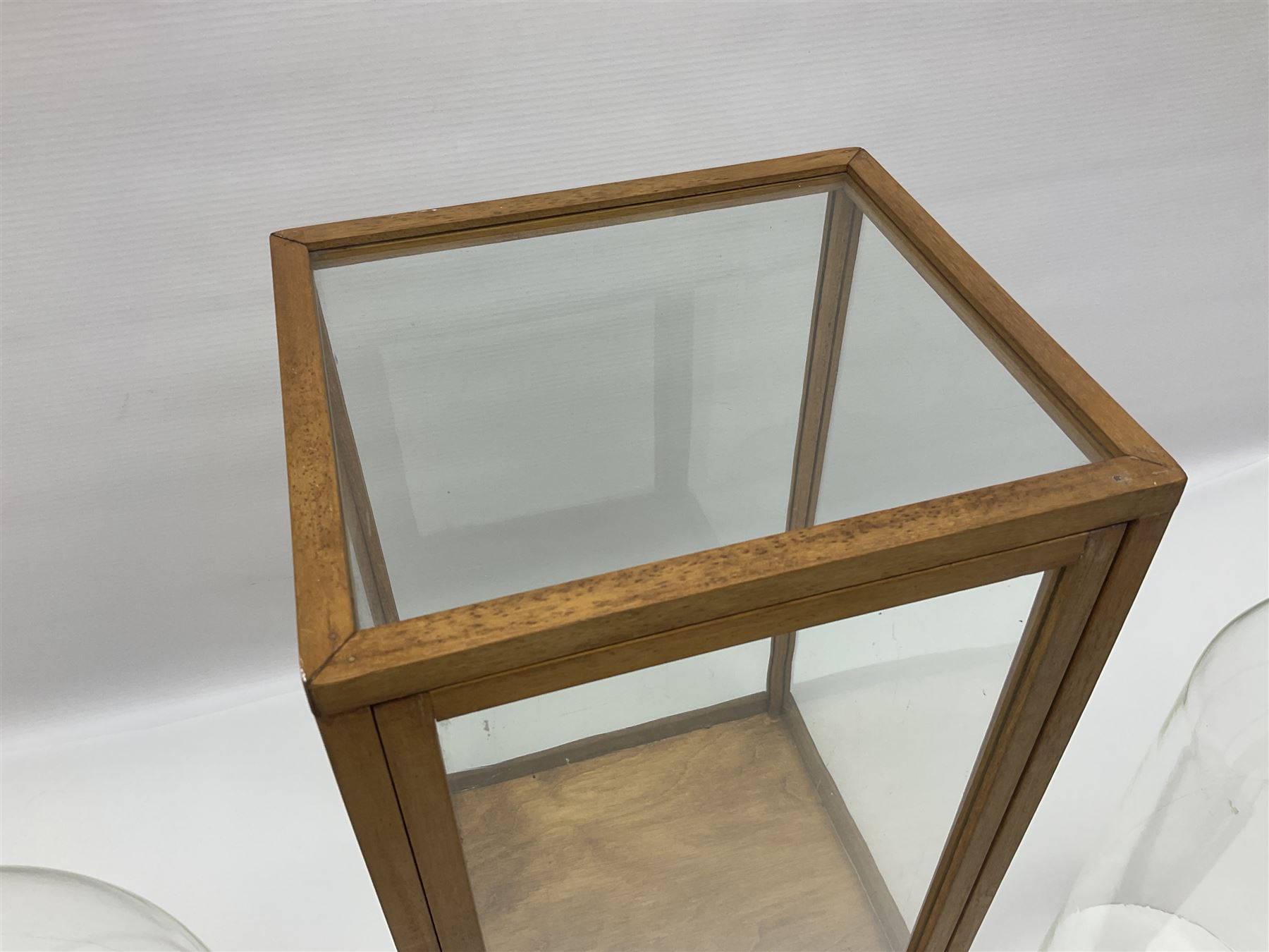 Tabletop glass display cabinet, with hinged door, together with two glass domes