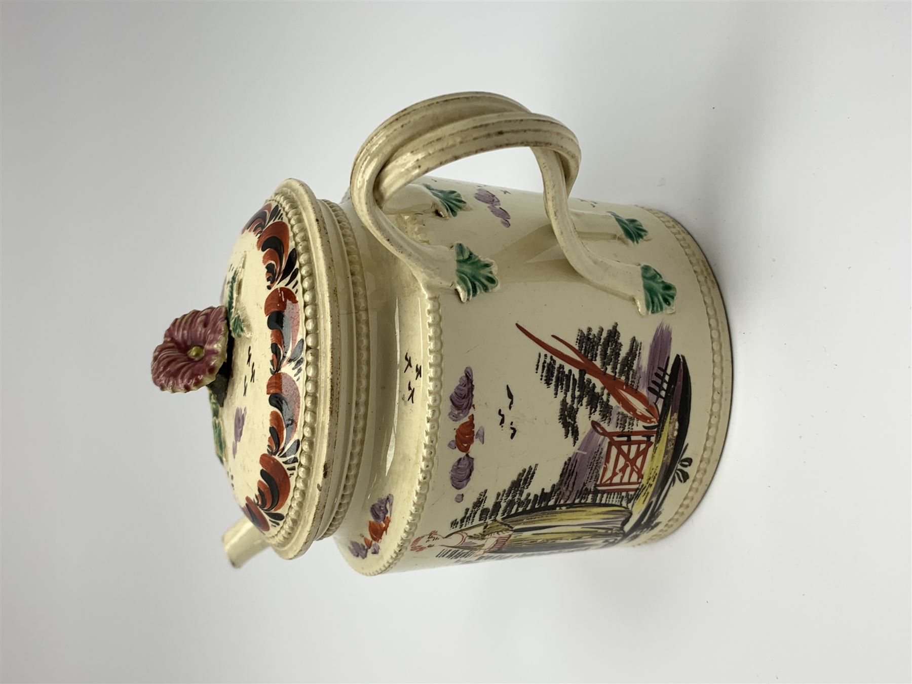 18th century creamware teapot, probably Leeds, with reeded entwined handle and floral finial to the cover, the body with hand painted polychrome decoration of figure to one side, and floral spray to the other, collectors paper label beneath inscribed Leeds Pottery, H11.5cm