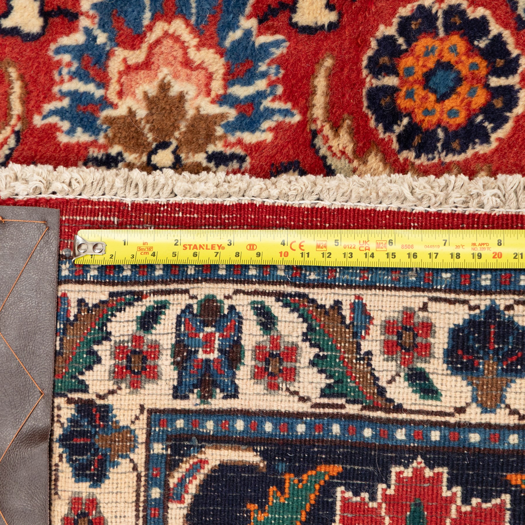 North West Persian carpet, the red field decorated with an all over repeating design of palmettes, rosettes and curling serrated leaves in indigo, ivory and ochre tones, enclosed by an indigo scrolling floral border and ivory flowerhead guard bands