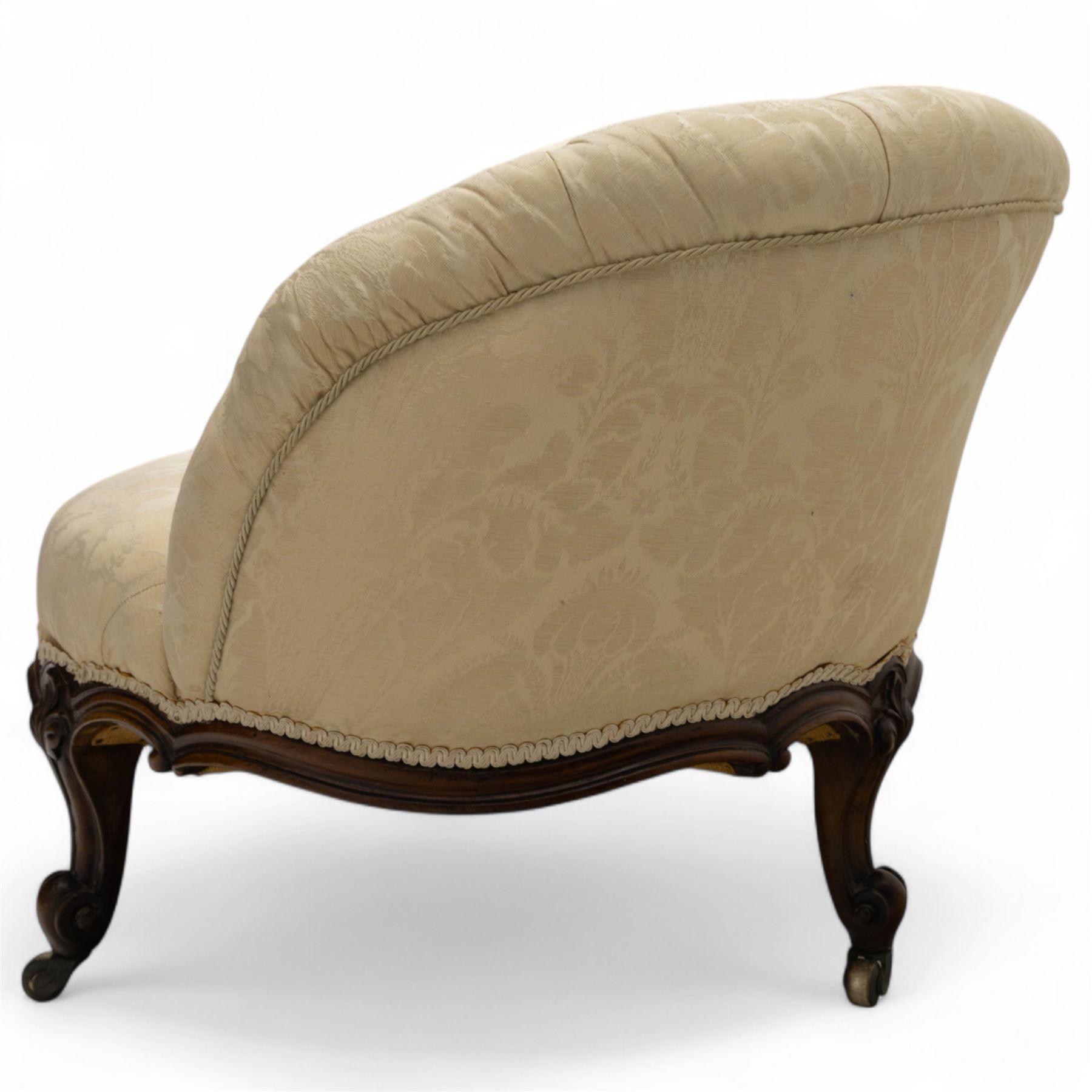 Late 19th century Victorian walnut button-back recamier, asymmetrical form, with cream damask fabric and gimp braid edging, shaped reeded apron above front and back scroll carved cabriole legs on brass castors