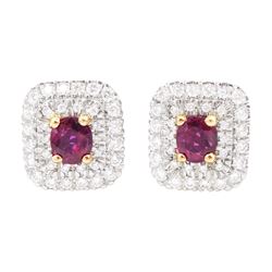 Pair of platinum ruby and diamond cluster earrings, each stud set with a single oval cut r...