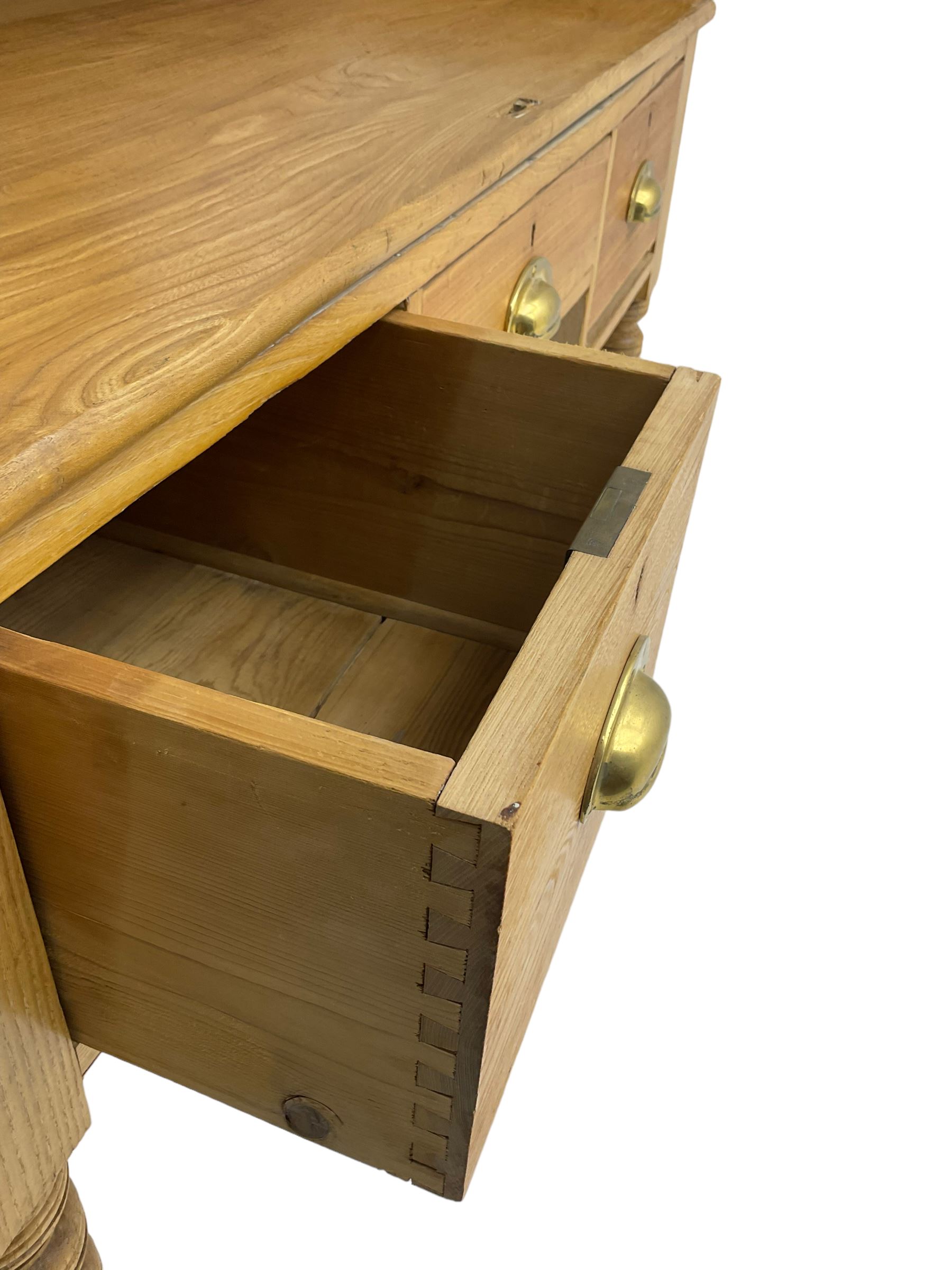 Early 20th century light oak kneehole desk, rectangular hinged top, fitted with frieze drawer flanked by two deep drawers, raised on ring turned supports