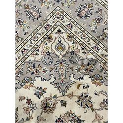 Persian Kashan ivory ground carpet, floral central medallion surrounded by trailing leafy branches and palmettes, floral pattern spandrels and matching border, within guard stripes