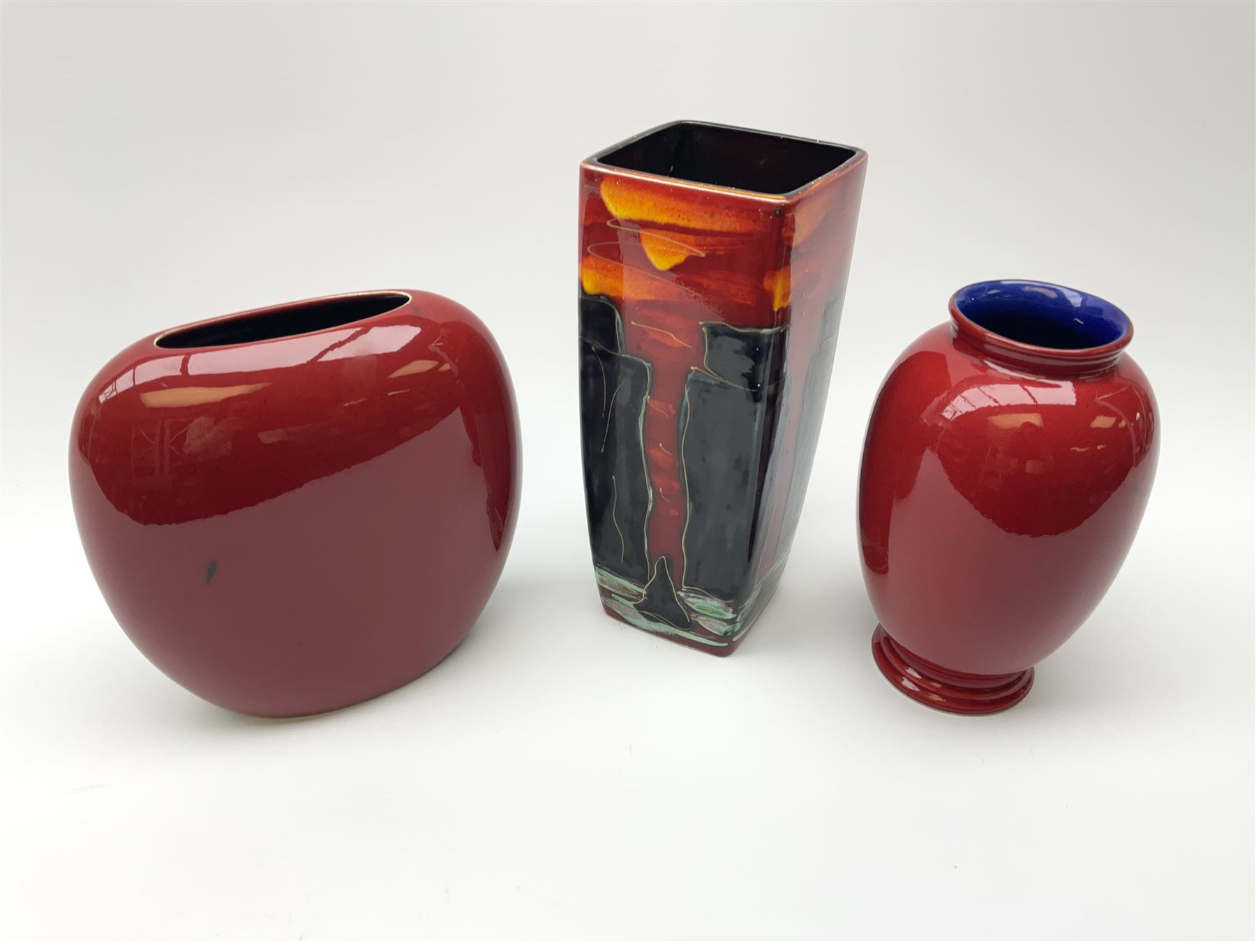 A Poole Pottery vase, of ovoid form decorated with green and yellow forms upon a red glazed ground, H20cm, together with two Anita Harris Art Pottery vase, with similar decoration. 