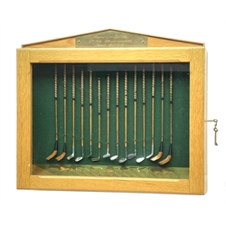 Modern handcrafted miniature set of fourteen 19th century style golf clubs by P.D. Rushworth dated 2000, each with turned wooden shaft and leather grip, comprising four woods including long nose driver, brassie and hooked face, and ten other metal head clubs including jigger, water iron, rut iron, anti-shank iron, wryneck iron, mammoth iron, Schenectady putter, etc., displayed in a baise lined architectural style oak case with hinged door, annotated brass strip and maker's plaque, longest club 28cm, case W52cm, H44cm