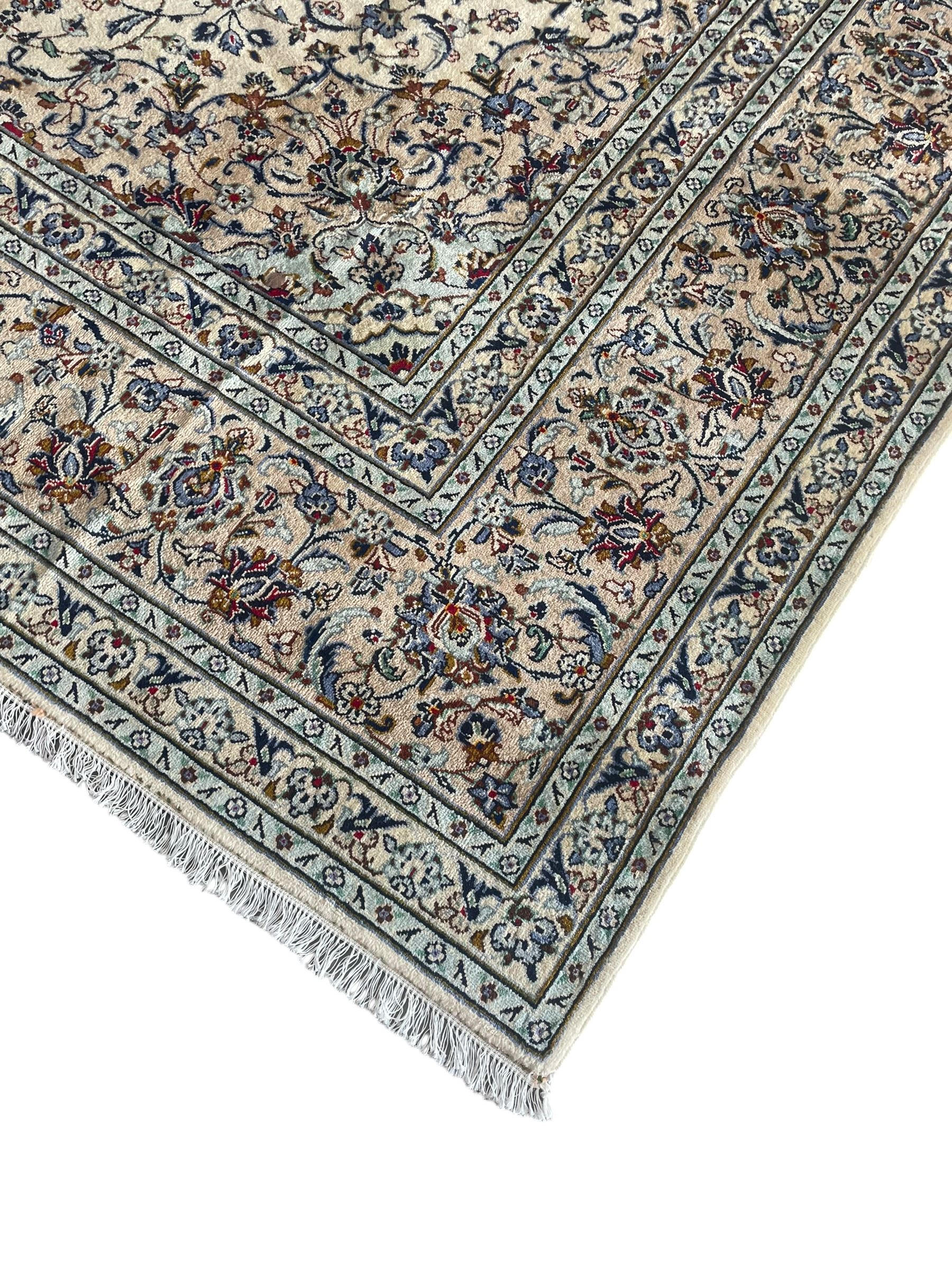 Persian Kashan ivory ground carpet, the field decorated with interlacing foliate branches and stylised plant motifs, scrolling border decorated with repeating palmettes, within floral pattern guard bands