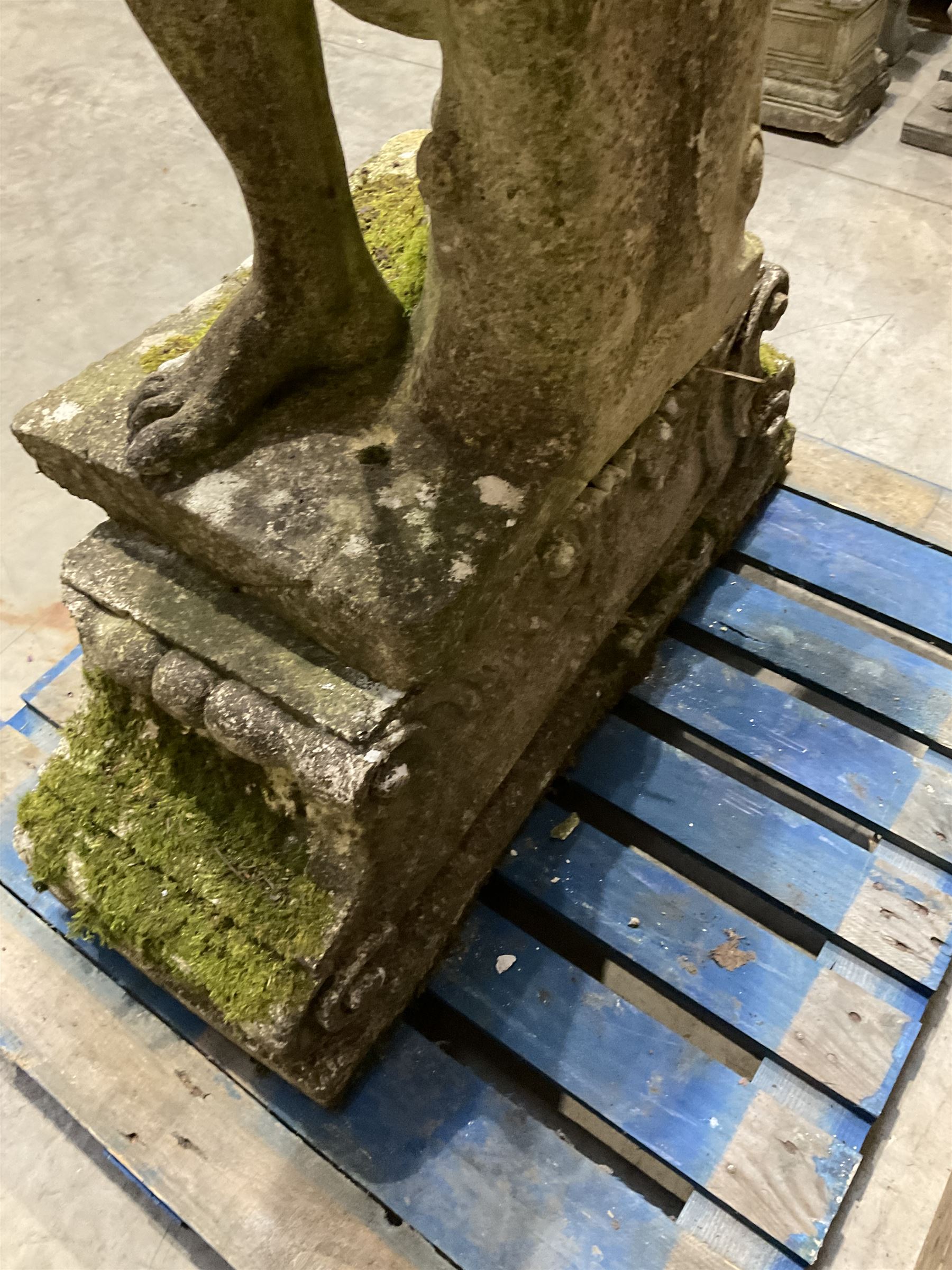 Life-size weathered cast stone Greek Discus Athlete, seated on rectangular slab raised on associated architectural plinth