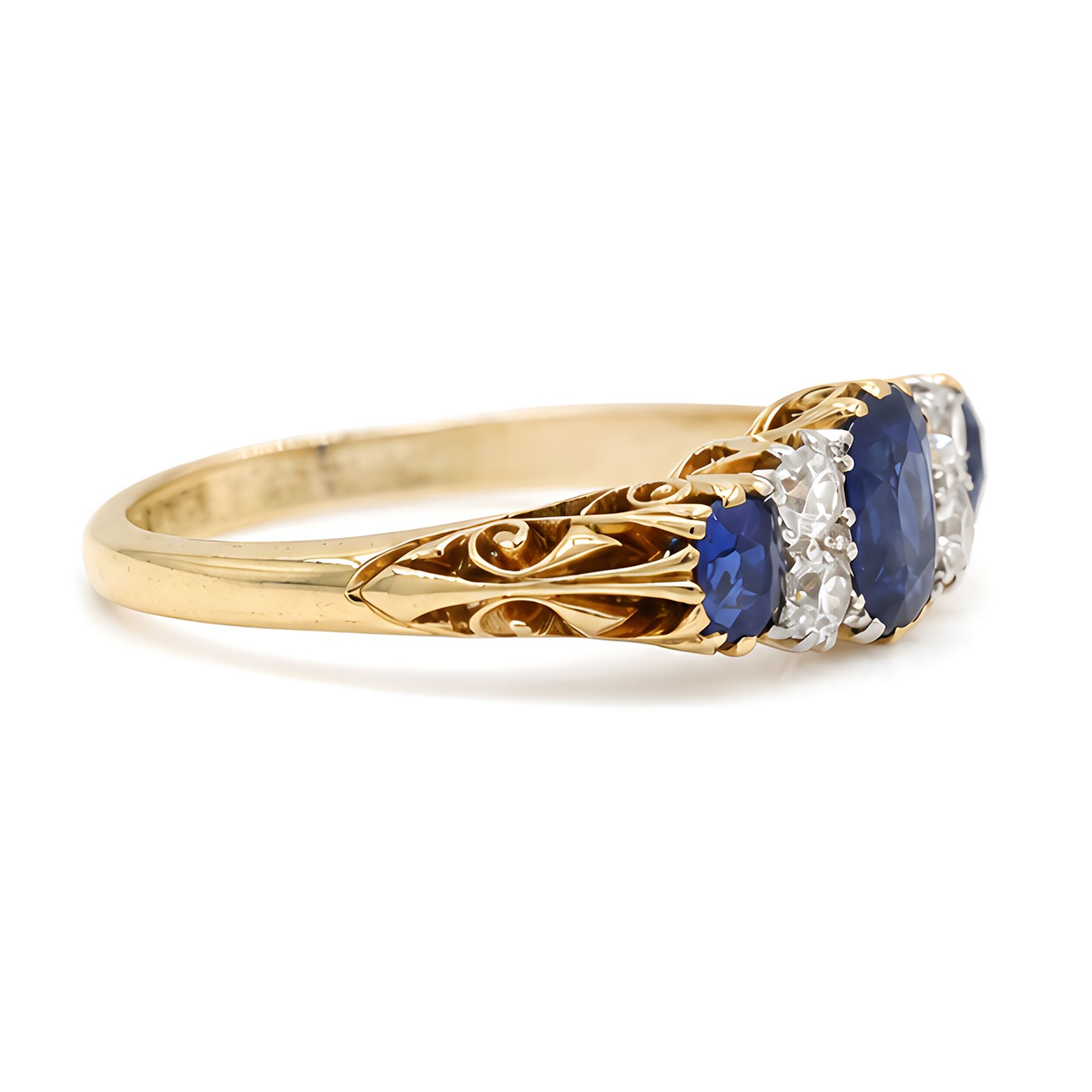 Early 20th century gold sapphire and diamond ring, three vari-cut sapphires, spaced by four old cut diamonds, with scroll design shoulders, stamped 18ct, total sapphire weight approx 1.45 carat, total diamond weight approx 0.30 carat