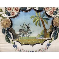 Early 20th century needlework depicting a leaping deer amongst grasses and tree, the shaped panel surrounded with floral sprays, in gilt frame, H49cm W47cm